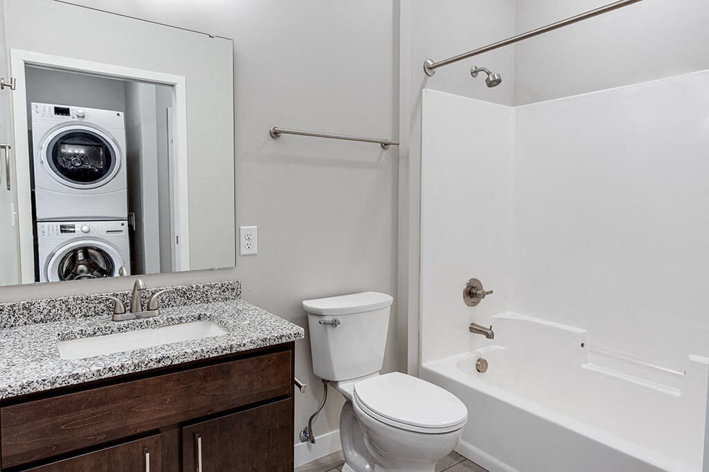 a bathroom with a washer and dryer in it  at RoCo Apartments, Fargo, North Dakota 58102