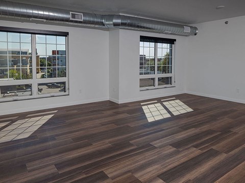 an empty room with hardwood floors and large windows at The Landing at 1001 NP, Fargo, ND 58102