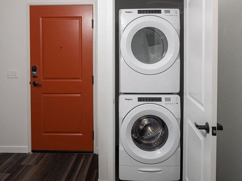 a white washer and dryer next to a red door at The Landing at 1001 NP, Fargo, North Dakota 58102