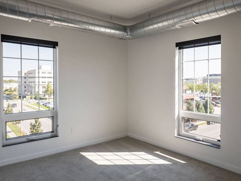 an empty room with two large windows at The Landing at 1001 NP, Fargo, ND 58102