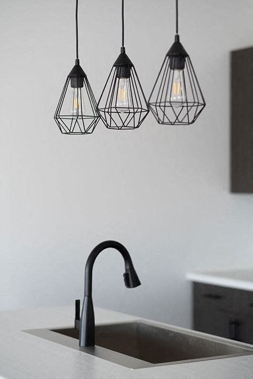 a kitchen sink with a black faucet and three lights at The Landing at 1001 NP, Fargo, North Dakota 58102