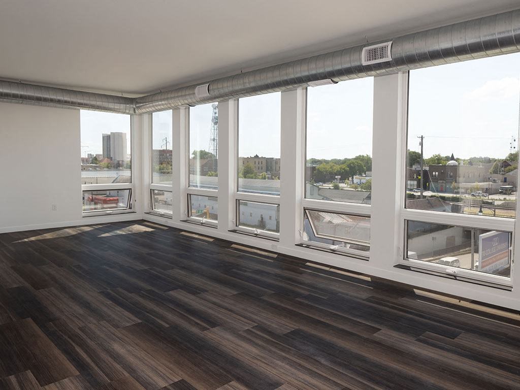 a living room with a large window and hardwood floors at The Landing at 1001 NP, Fargo, ND 58102