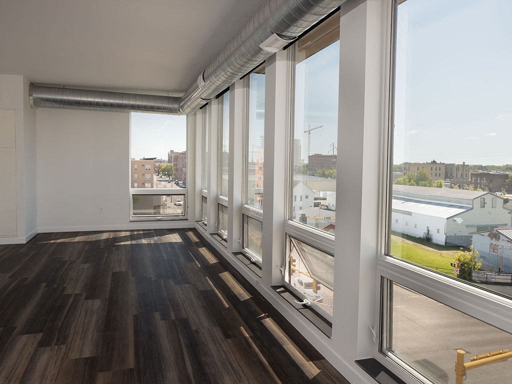 a living room with large windows and a wooden floor at The Landing at 1001 NP, Fargo, North Dakota 58102