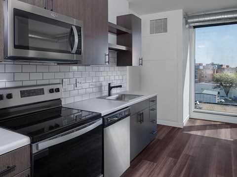 a kitchen with a stove top oven next to a window at The Landing at 1001 NP, Fargo, ND, 58102