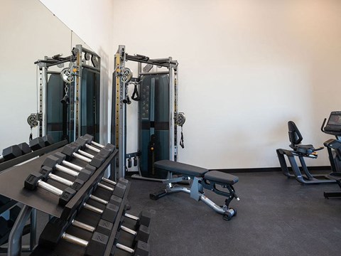 a room filled with cardio equipment and weights at The Landing at 1001 NP, Fargo, North Dakota 58102