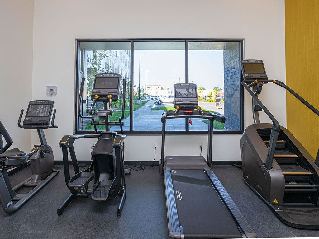 a treadmill and three treadmills in a gym with a large window at The Landing at 1001 NP, Fargo, ND 58102