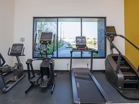 a treadmill and three treadmills in a gym with a large window at The Landing at 1001 NP, Fargo, ND 58102