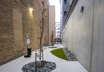 A courtyard with a tree and rocks next to a brick building at Kesler Apartments, Fargo, ND 58102