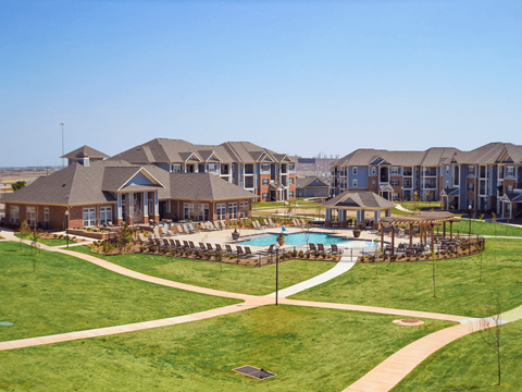 A large grassy area with a pool and a building in the background.