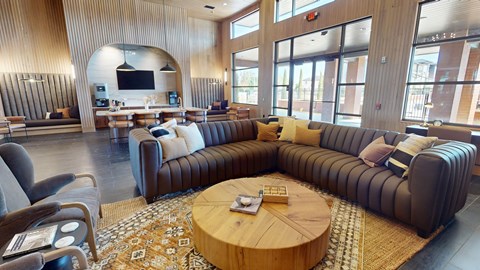 A living room with a large couch and a TV mounted on the wall.