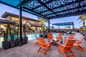 a patio with orange chairs and a fire pit and a pool in the background