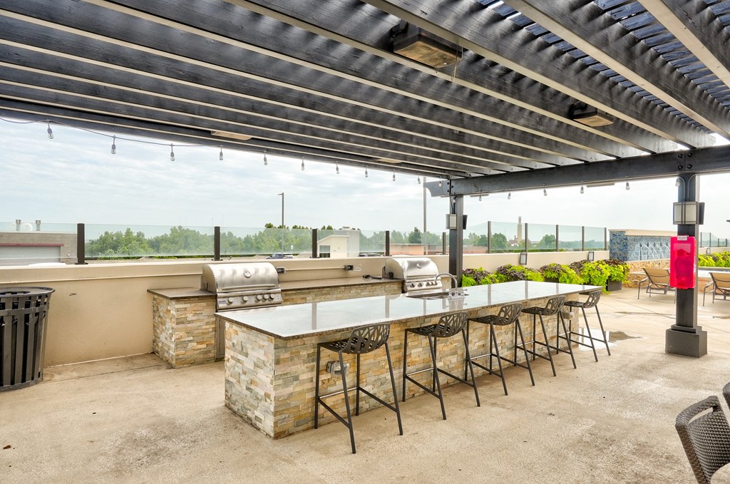 an outdoor patio with a barbecue grill and a long table with stools