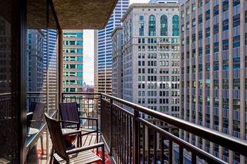 a balcony with chairs and a table and a view of skyscrapers