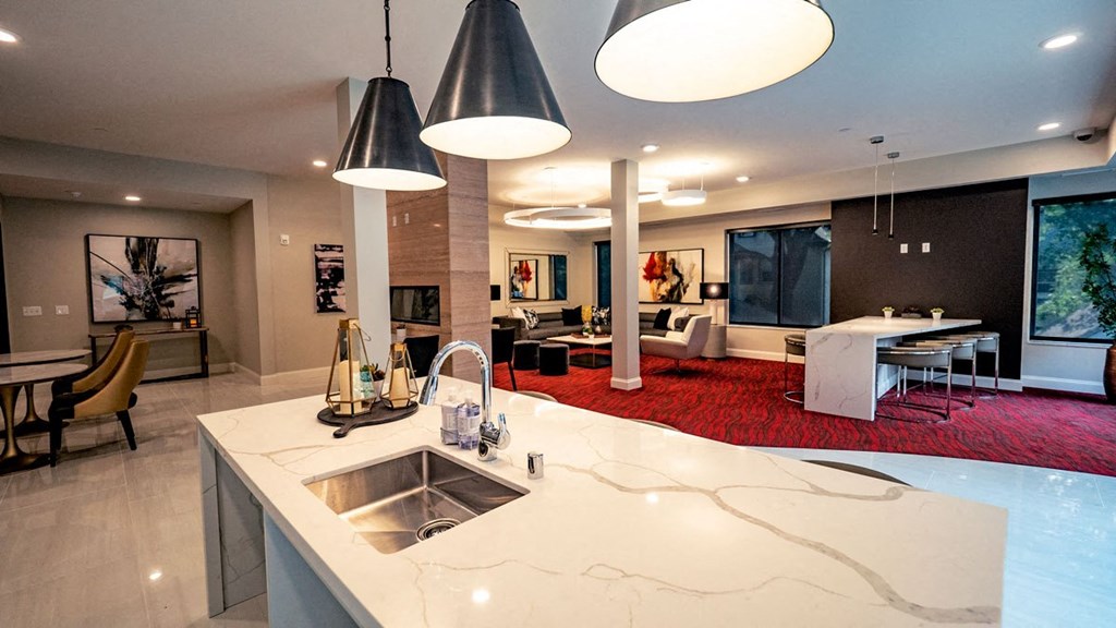 a kitchen with a counter and a living room with tables and chairs