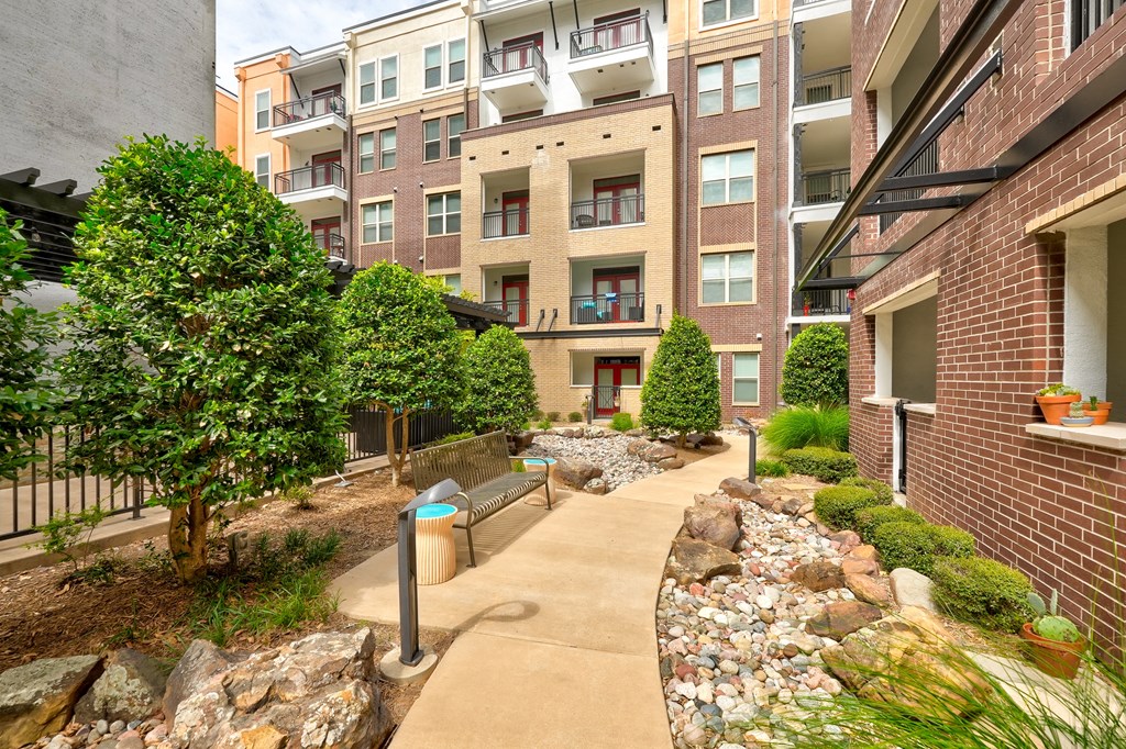 a walkway with benches in front of an apartment building