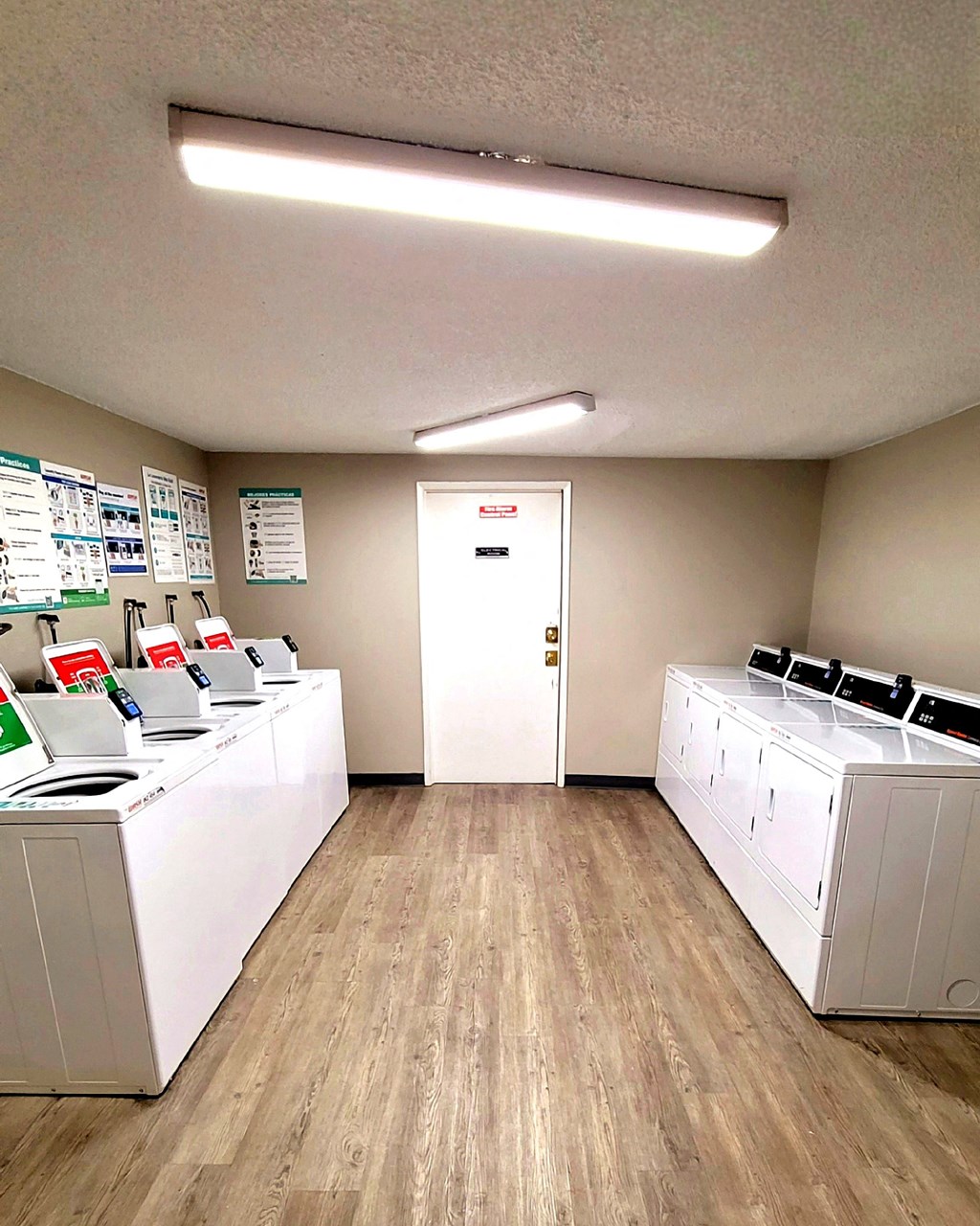 A laundromat with washers and dryers lined up on both sides of the room.