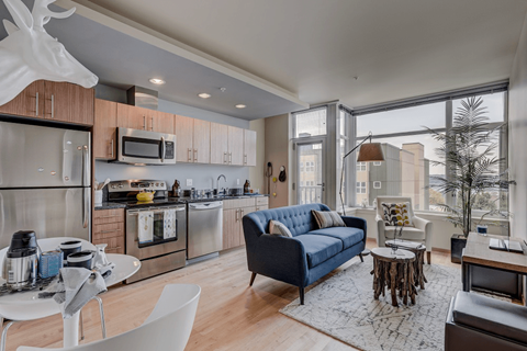 a living room with a couch and a kitchen with a large window