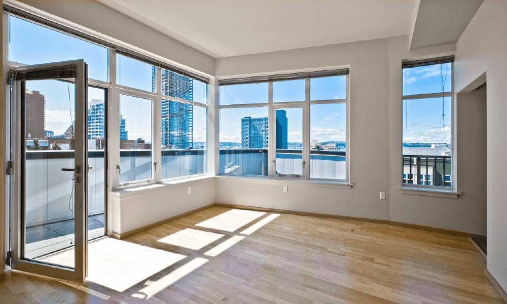 a living room with large corner windows with a view of the city