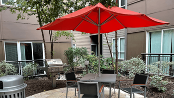 Lush green courtyard with tranquil water feature, tree-lined seating and grilling/dining areas