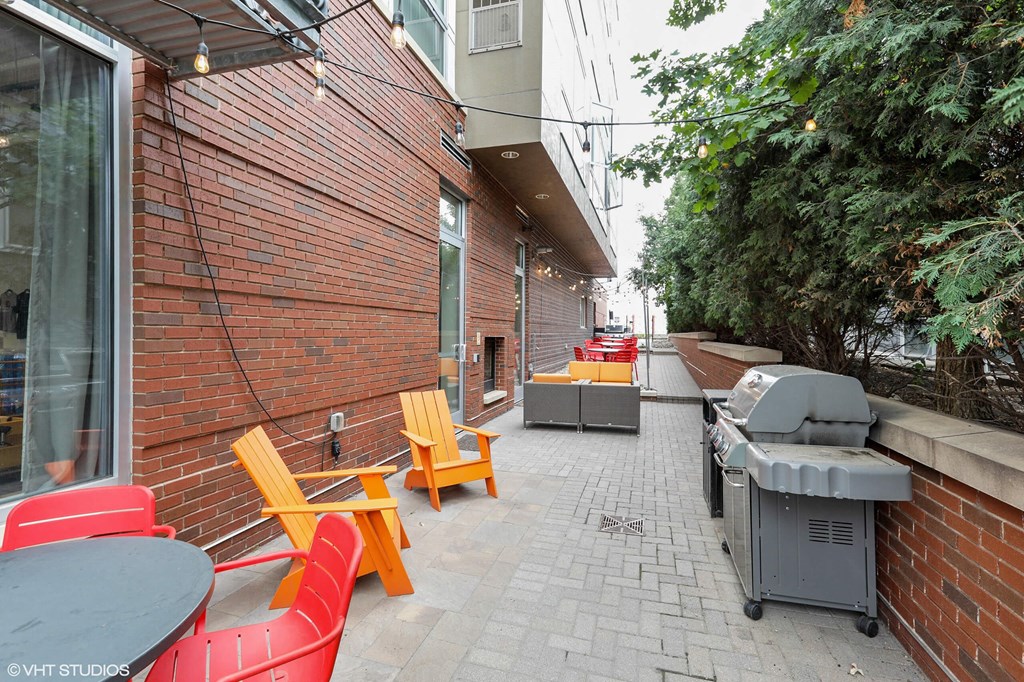 A patio with red and yellow chairs and a grill.
