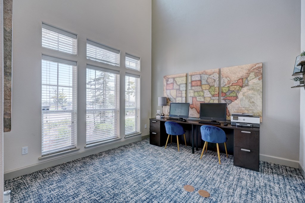 a desk with two computers and a map on the wall