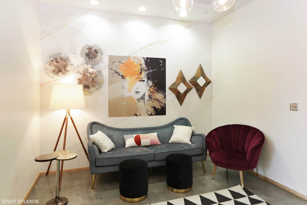 A living room with a grey couch, a red chair, and a black and white rug.