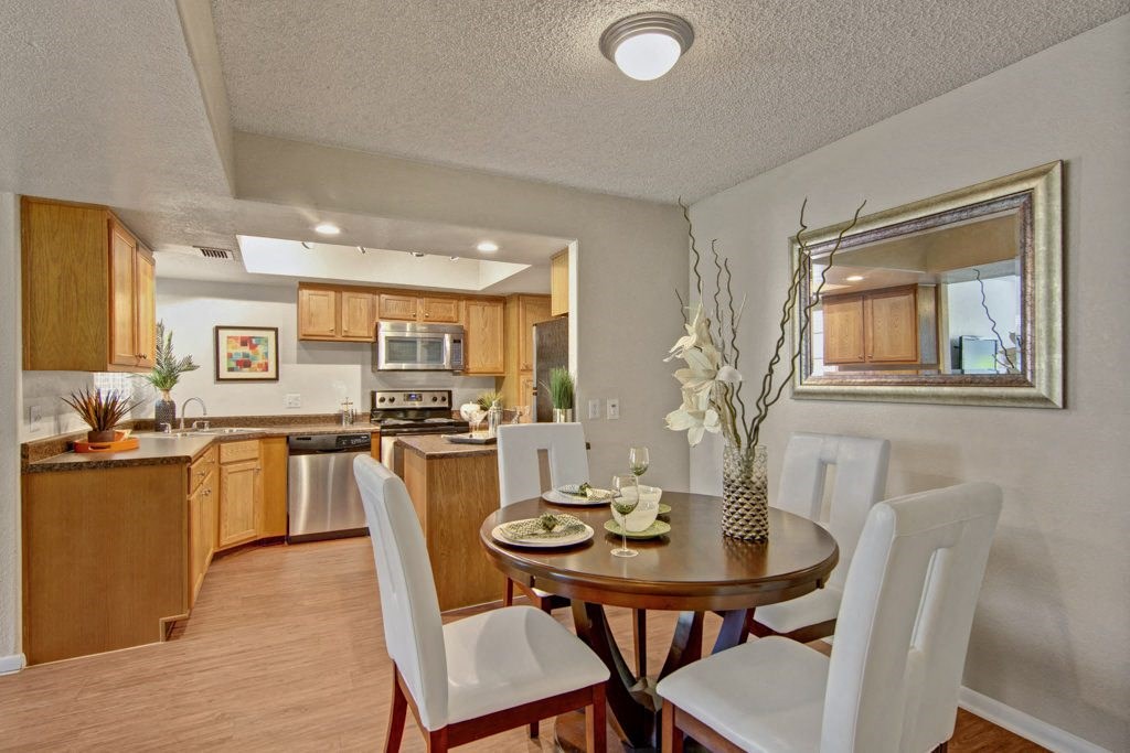 a dining area with a table and chairs and a kitchen in the background