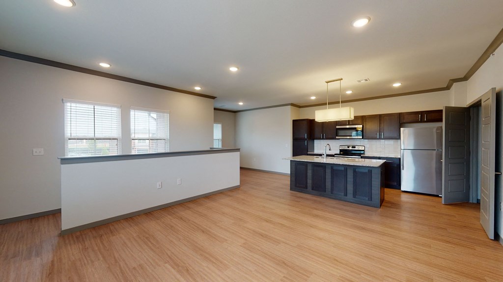 Modern kitchen here at 35 Degrees North Apartment Homes with stainless steel appliances, dark wood cabinets, and a granite island. Open floor plan with bamboo flooring and recessed lighting.