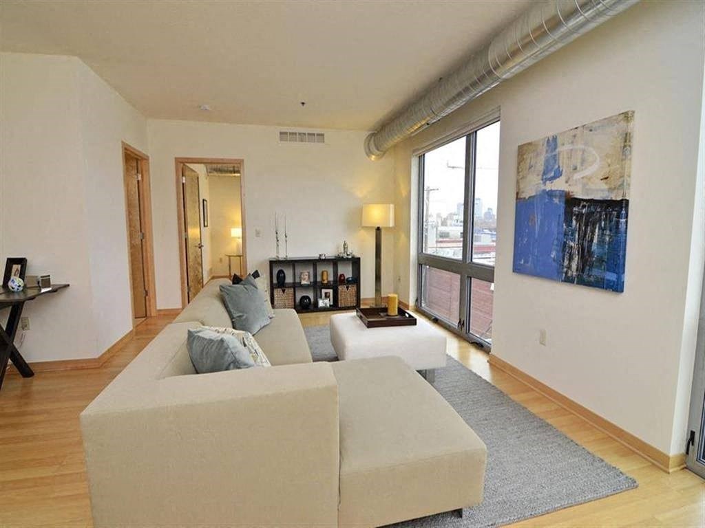 A living room with a grey couch and a painting on the wall.