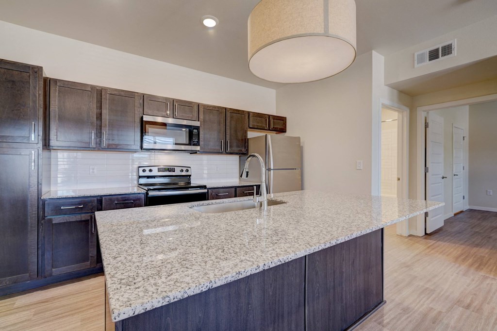 a kitchen with a large island and a stainless steel refrigerator