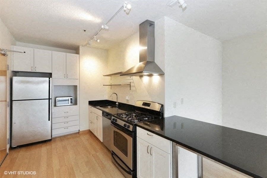 A kitchen with black countertops and stainless steel appliances.