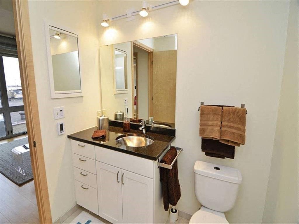 A bathroom with a white toilet and a sink with a brown towel hanging on the towel rack.