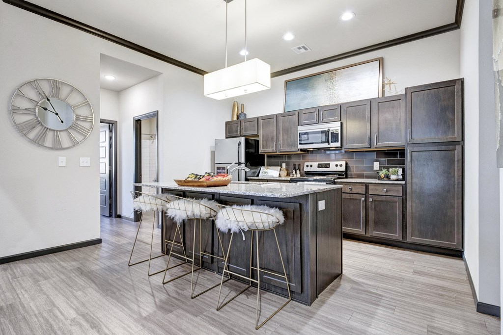a kitchen with a large island with bar stools and a clock on the wall