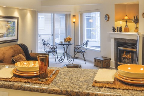 A living room with a fireplace and a dining table set for two.