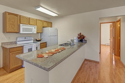 A kitchen with a granite counter top and wooden cabinets.