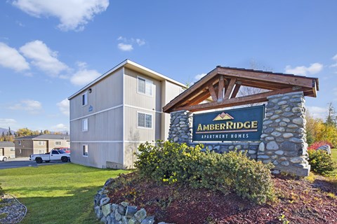 A building with a sign that says "AmberRidge Apartment Homes" in front of it.