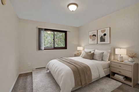 Cozy bedroom at Arbor Pointe with a large bed dressed in white bedding and a tan throw blanket, matching nightstands with lamps, wall art above the bed, and a window bringing in natural light from outside greenery
