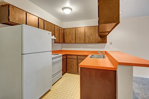 A kitchen with a white refrigerator, wooden cabinets, and a countertop.