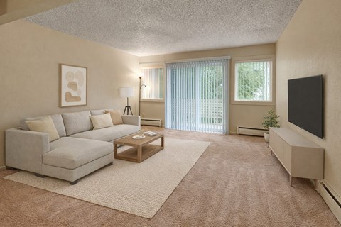 A spacious living room at Arctic Sun Apartments with a light sectional sofa, coffee table, and a TV on a media stand. Neutral carpet and walls create a warm feel. Large windows and a sliding glass door with vertical blinds provide natural light and lead to an outdoor patio space.