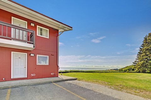 A red building with a balcony and a white door is in the foreground with a clear blue sky above.