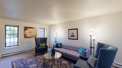 A living room with a grey couch, a blue chair, a coffee table, and a painting on the wall.
