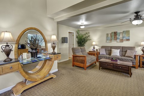 A living room with a couch, chair, and a table with a lamp on it.