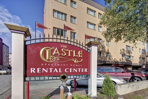 The sign for The Castle Apartment Homes Rental Center is red and gold.