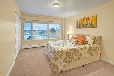 A bedroom with a large bed and a view of a snowy landscape outside the window.