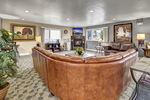 A living room with a brown leather couch and a fireplace.