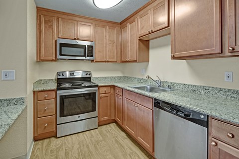 A kitchen with wooden cabinets and granite countertops.