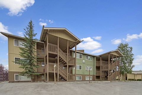 A large apartment complex with a parking lot in front.