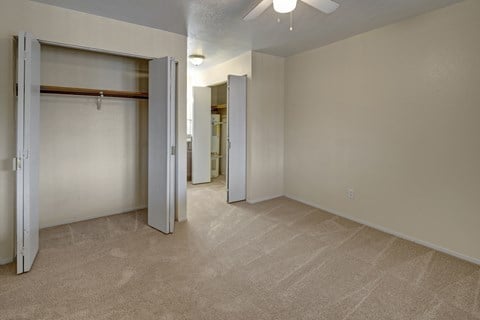 A room with a carpeted floor and a ceiling fan.