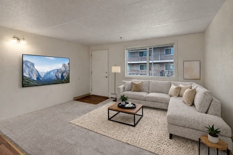 A living room with a grey couch, a coffee table, and a painting of a mountain scene on the wall.