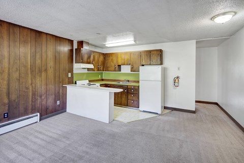 A kitchen area with a white counter and wooden cabinets.